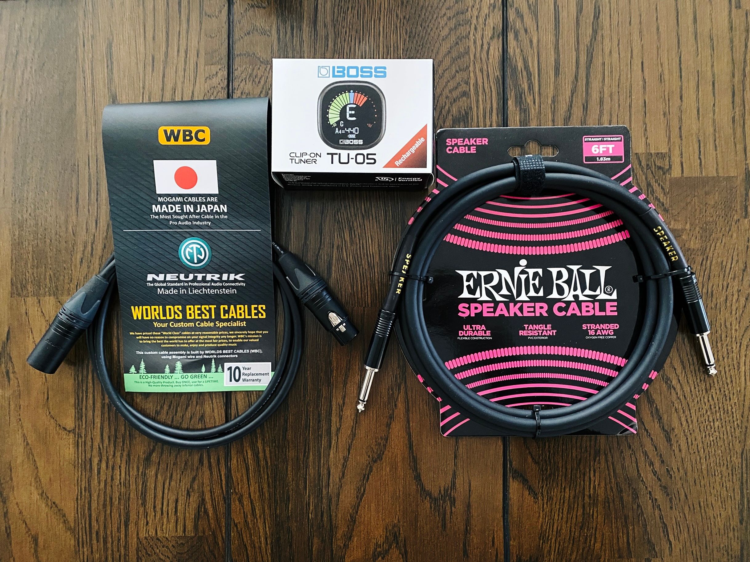 A photo of an Ernie Ball speaker cable (for hooking the guitar amp into the load box), a "World's Best Cables" XLR cable (for hooking the load box into the USB audio interface), and a Boss-brand digital tuner that clips onto the guitar headstock.