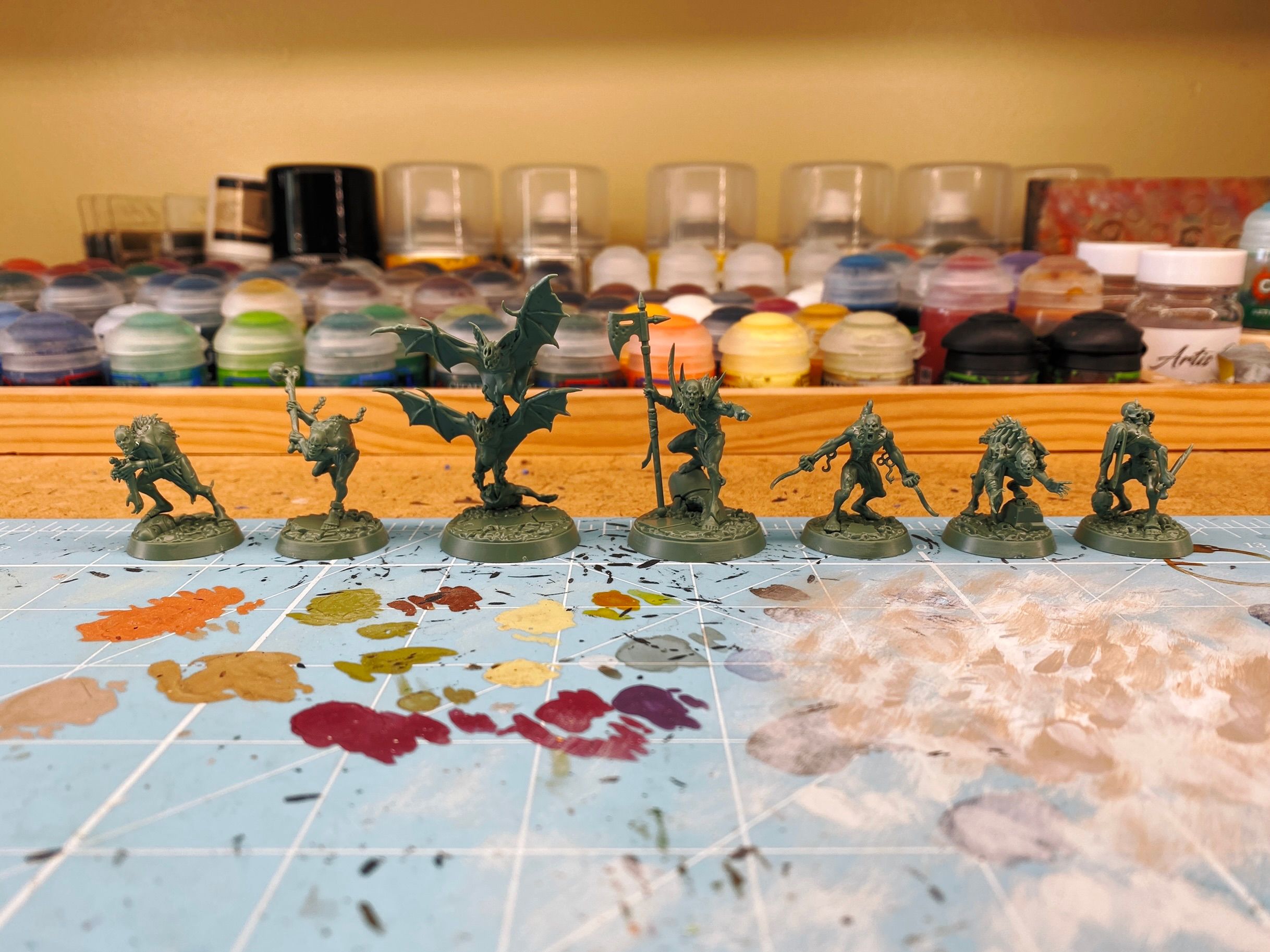 A photo of the Grymwatch warband assembled, in sickly green plastic. Seven miniatures, six are zombies, one's holding an axe and pointing, the others are hunched over in various poses. There's also a pair of very large bats.