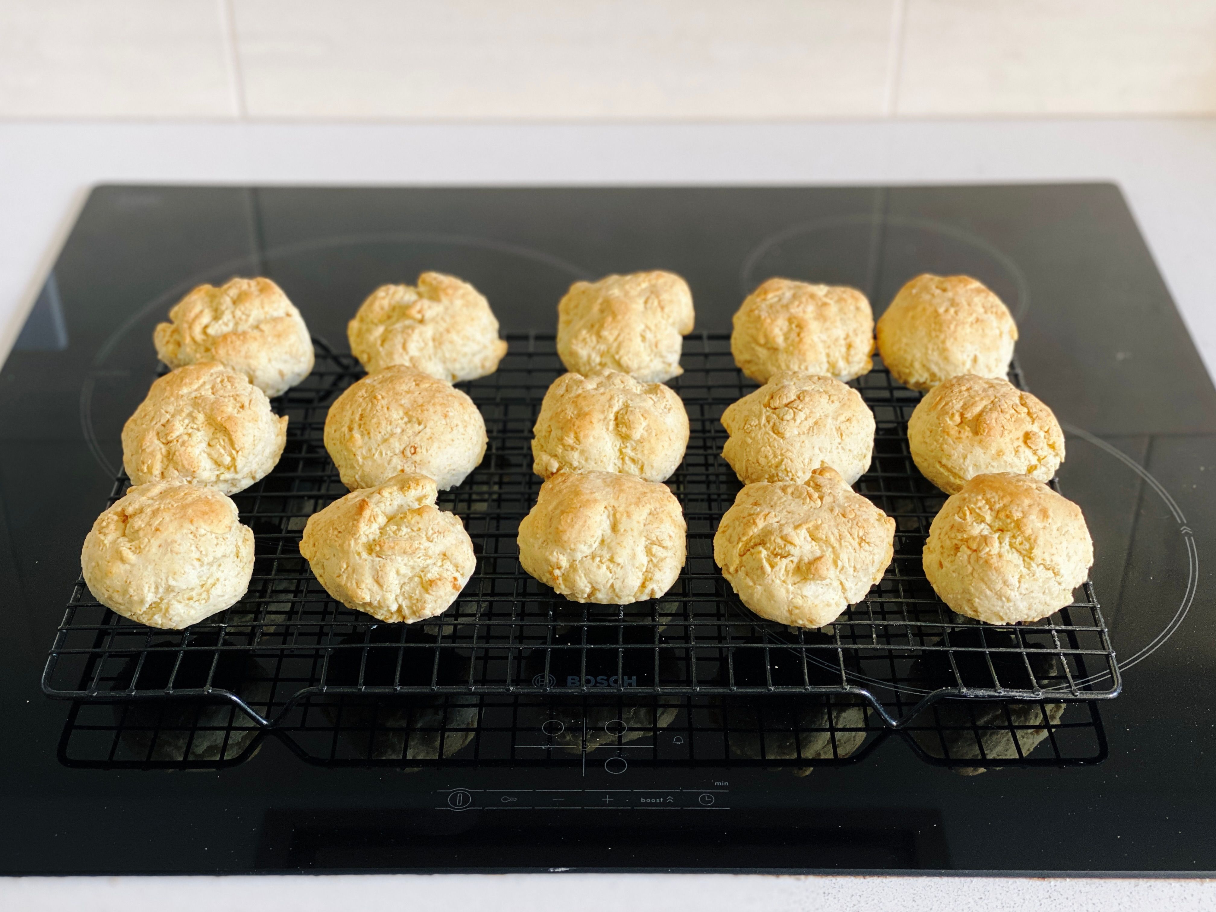 A photo of fifteen lightly golden cut rounds (basically scones but more savoury) sitting on a cooling rack.