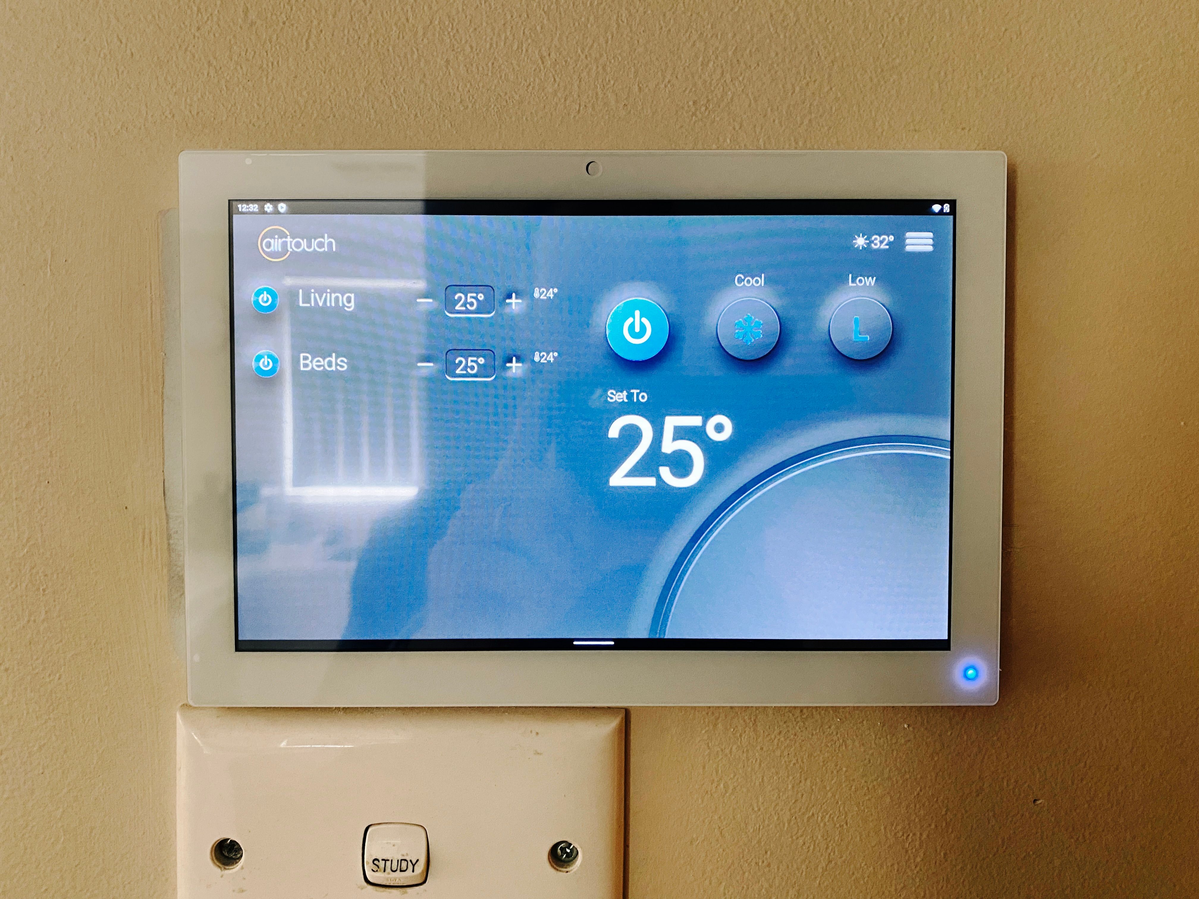 A photo of a small Android tablet attached to the wall, showing two zones "Living" and "Beds" with separate temperature settings for each.