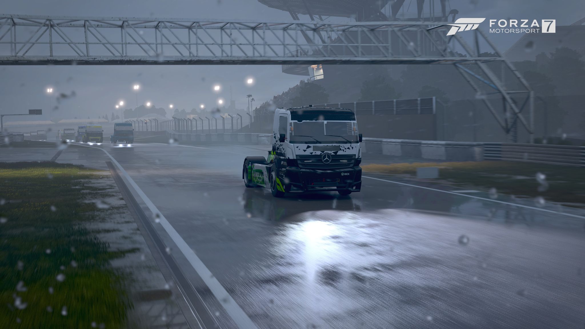 A screenshot from Forza Motorsport 7 showing a truck cab racing along a rainy stretch of road with its headlights on, water spraying up behind it, and rain drops on the camera lens.
