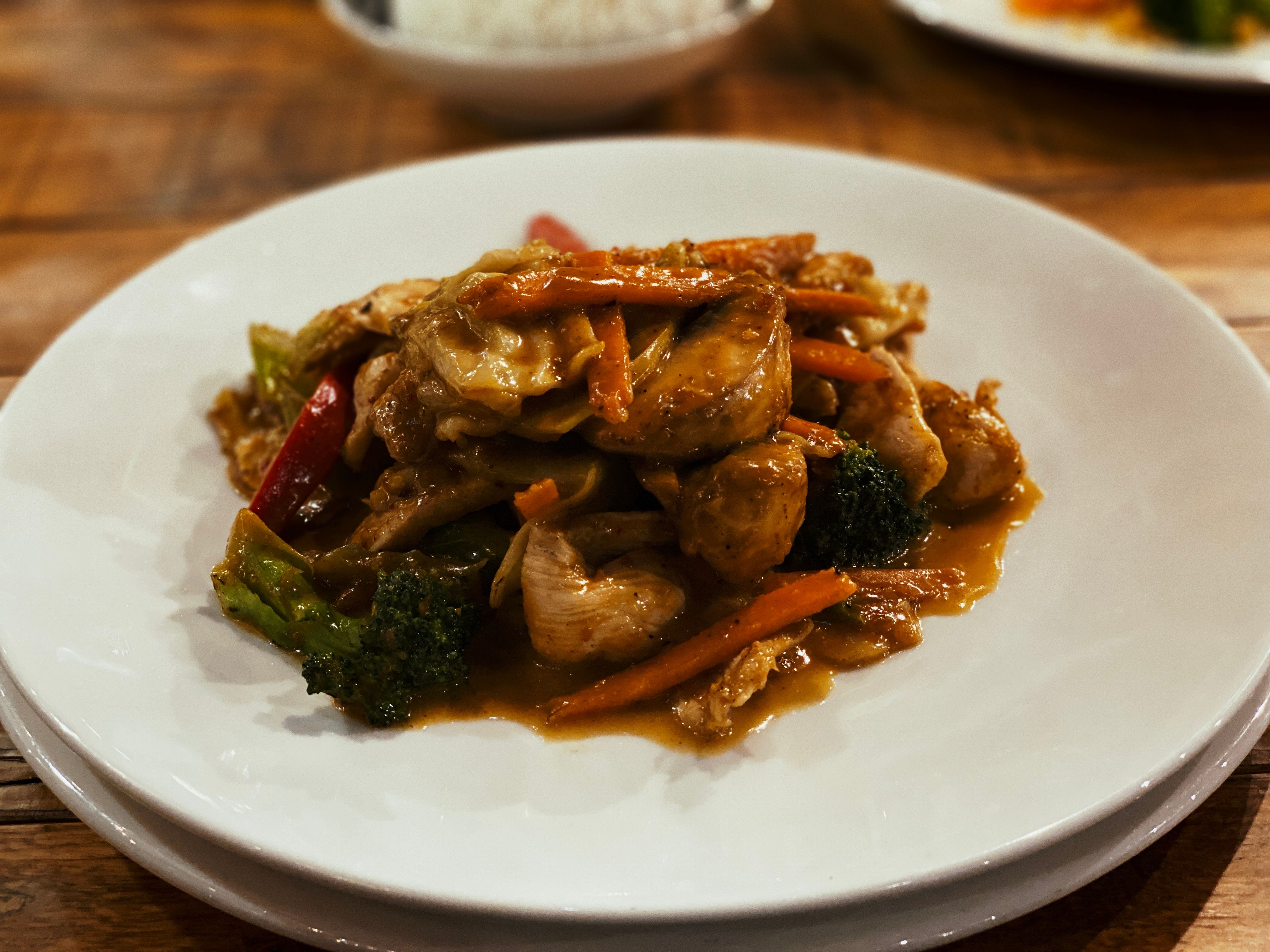 A photo of satay chicken with mixed vegetables on a plate.