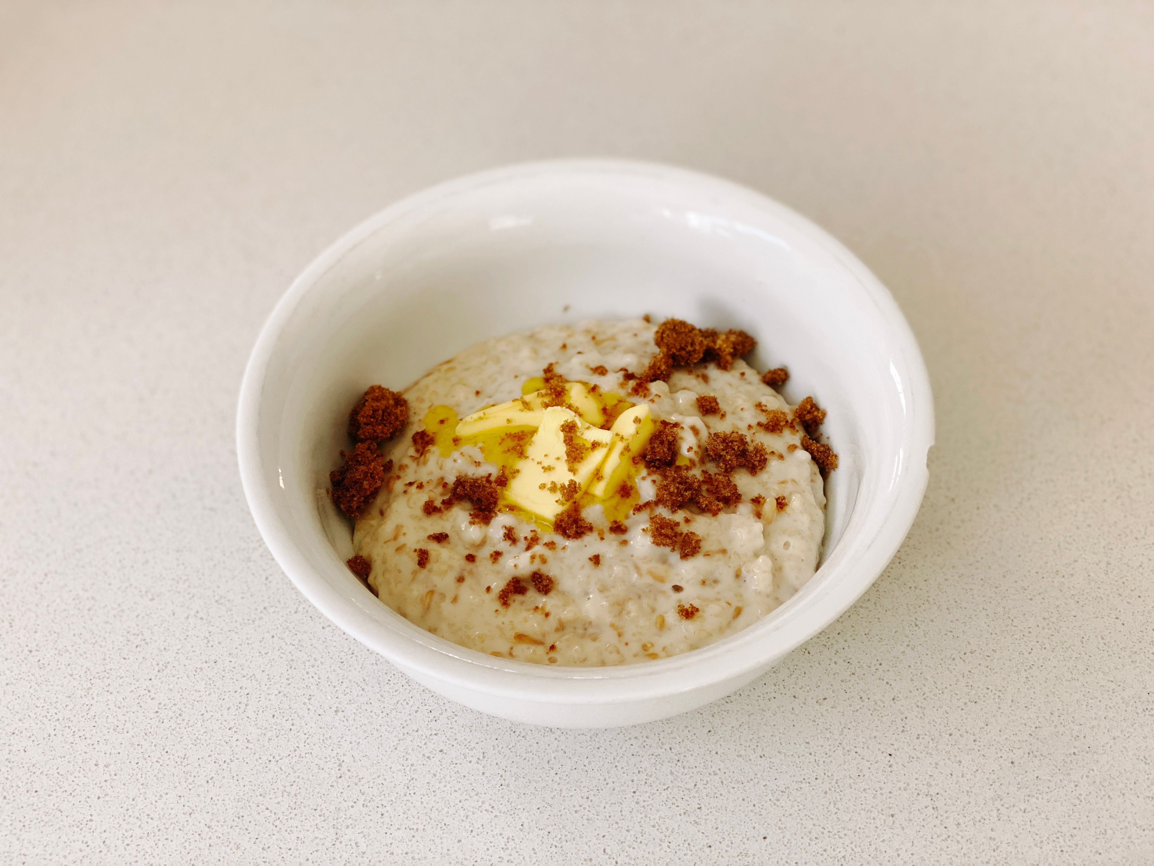 A photo of a bowl of porridge with butter and brown sugar on top.
