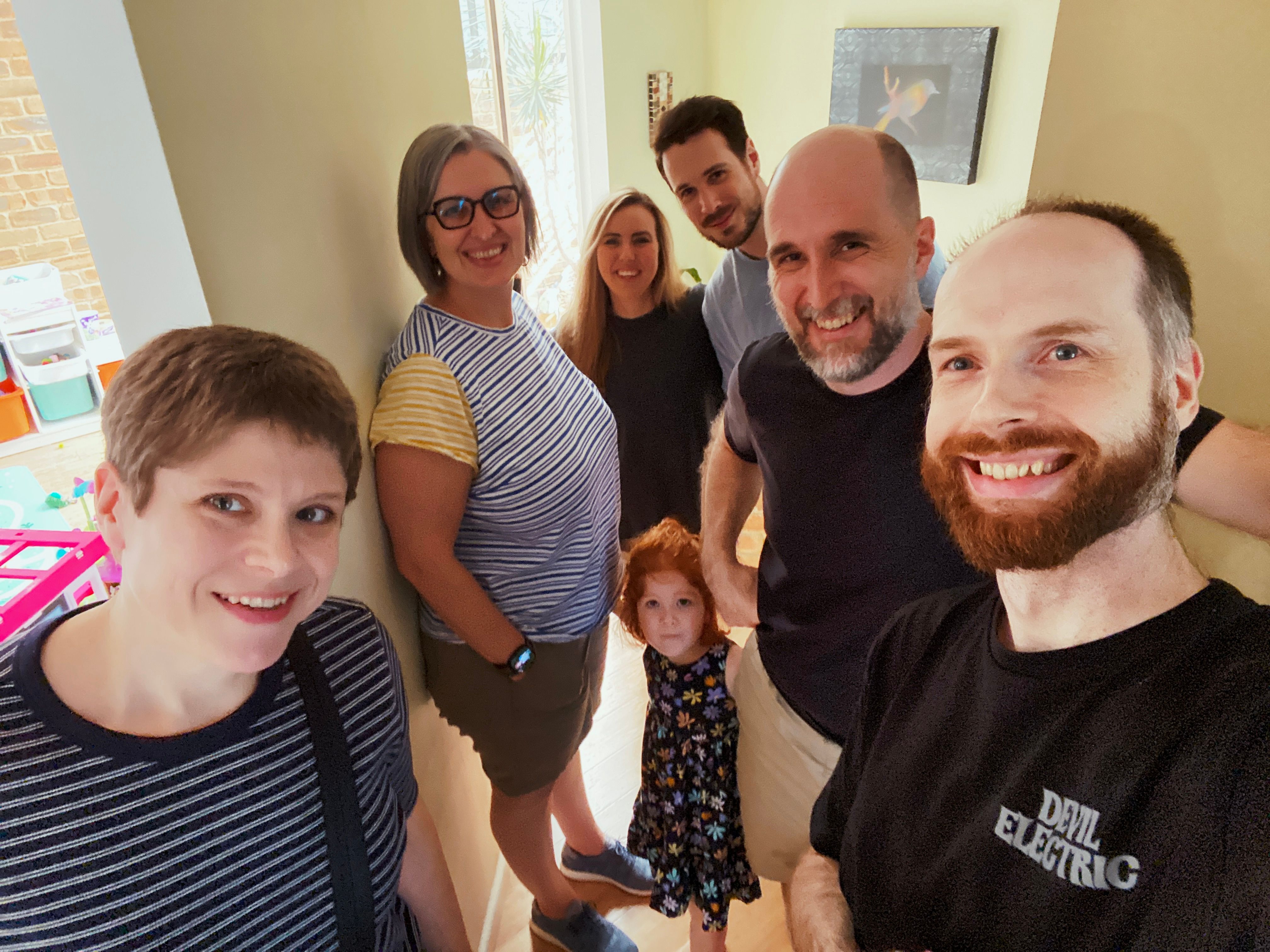 A photo of six adults (and one very red-haired three year-old) smiling at the camera.