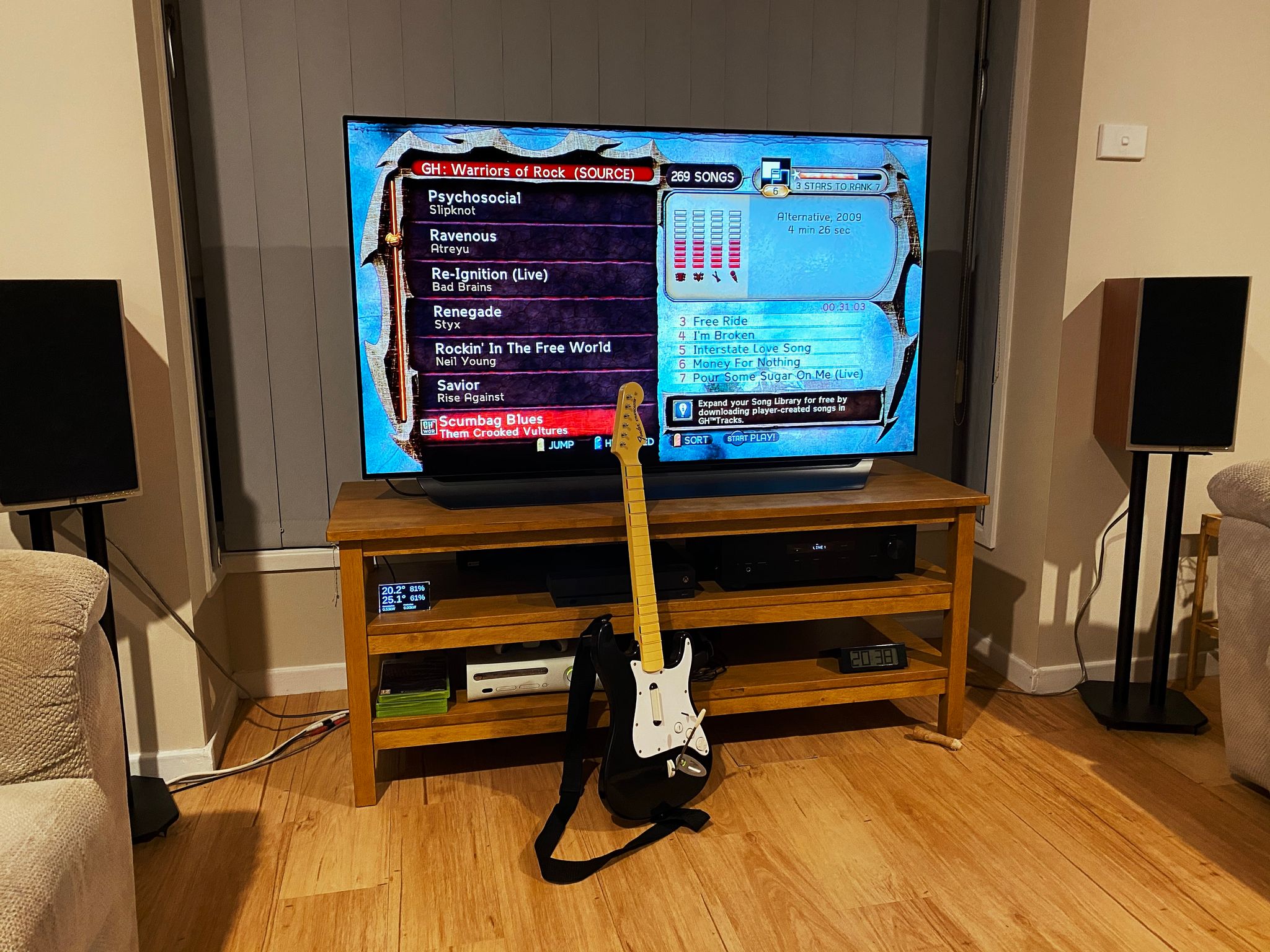 A photo of our lounge room, showing Guitar Hero: Warriors of Rock on the TV, and one of the guitar controllers sitting in front of it.