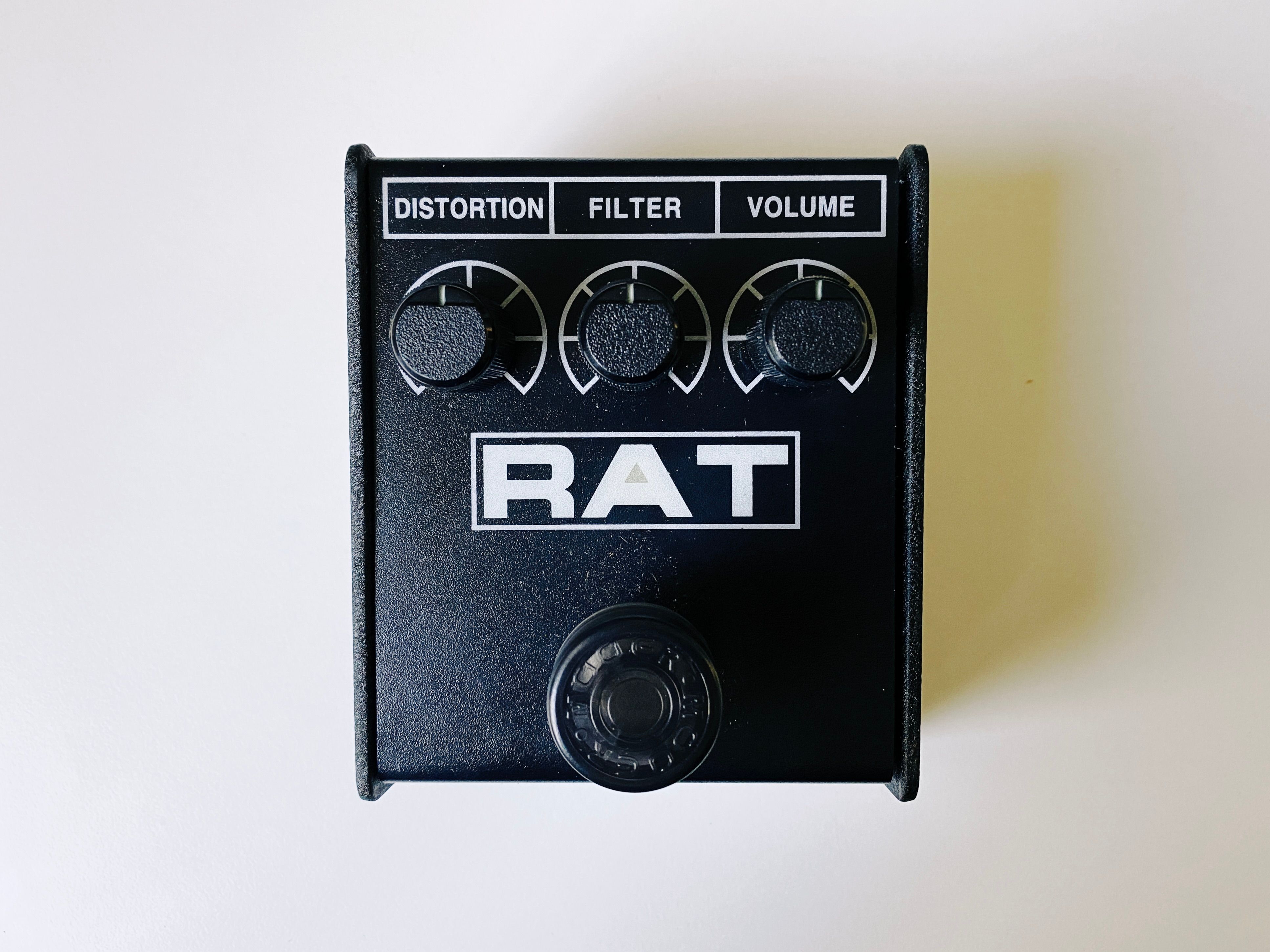 A photo of a square black guitar pedal with "RAT" written on it. There's three dials labelled Distortion, Filter, and Volume, and a clicky footswitch to turn it on and off.