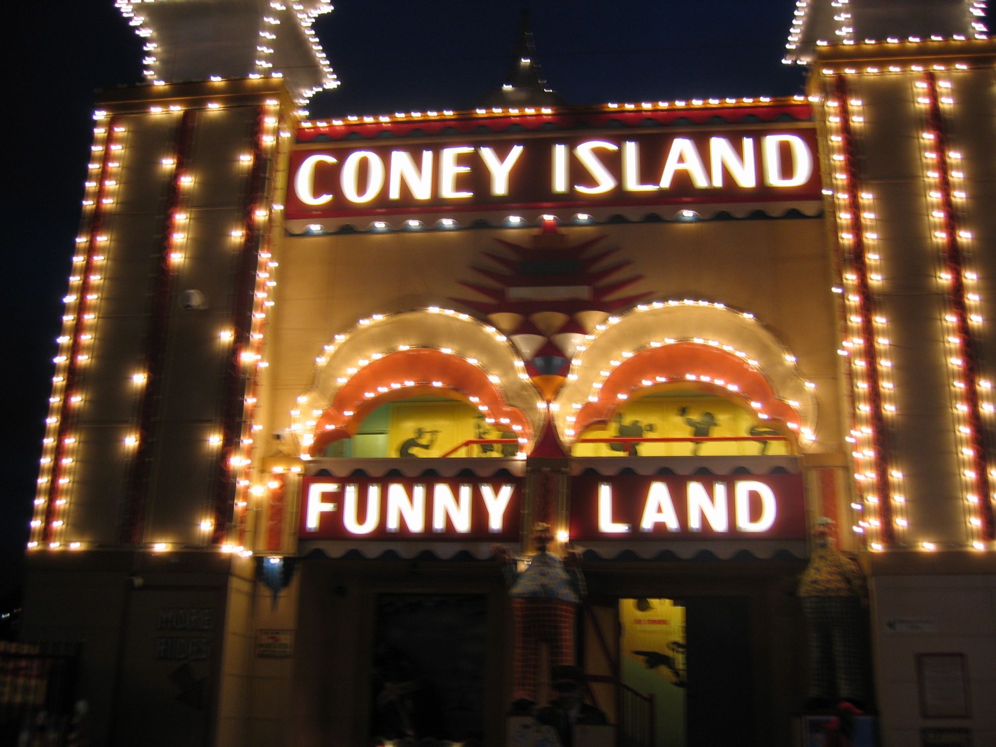 A photo of a lit-up entrance that says "Coney Island - Funny Land" in big glowing letters.