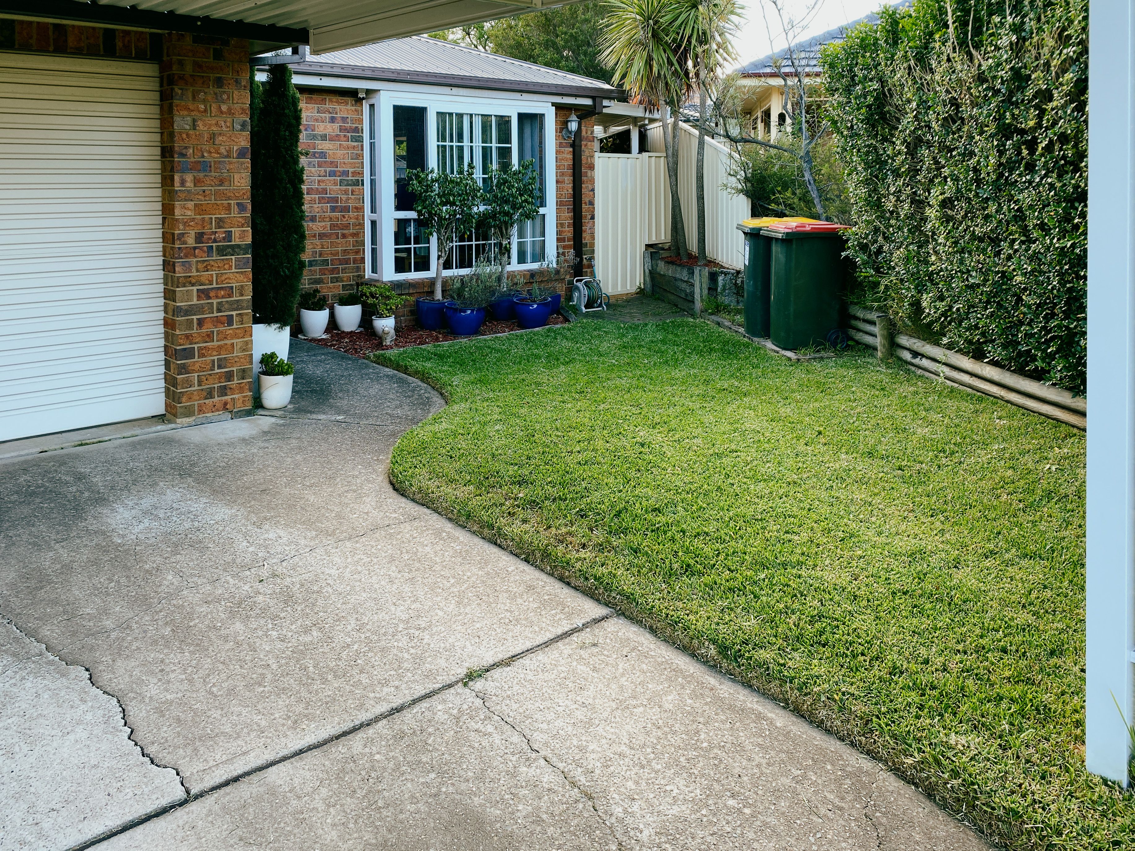 A photo taken from under our carport looking at part of the front yard and the front of the house. The grass is neat and tidy and the edging perfectly done.