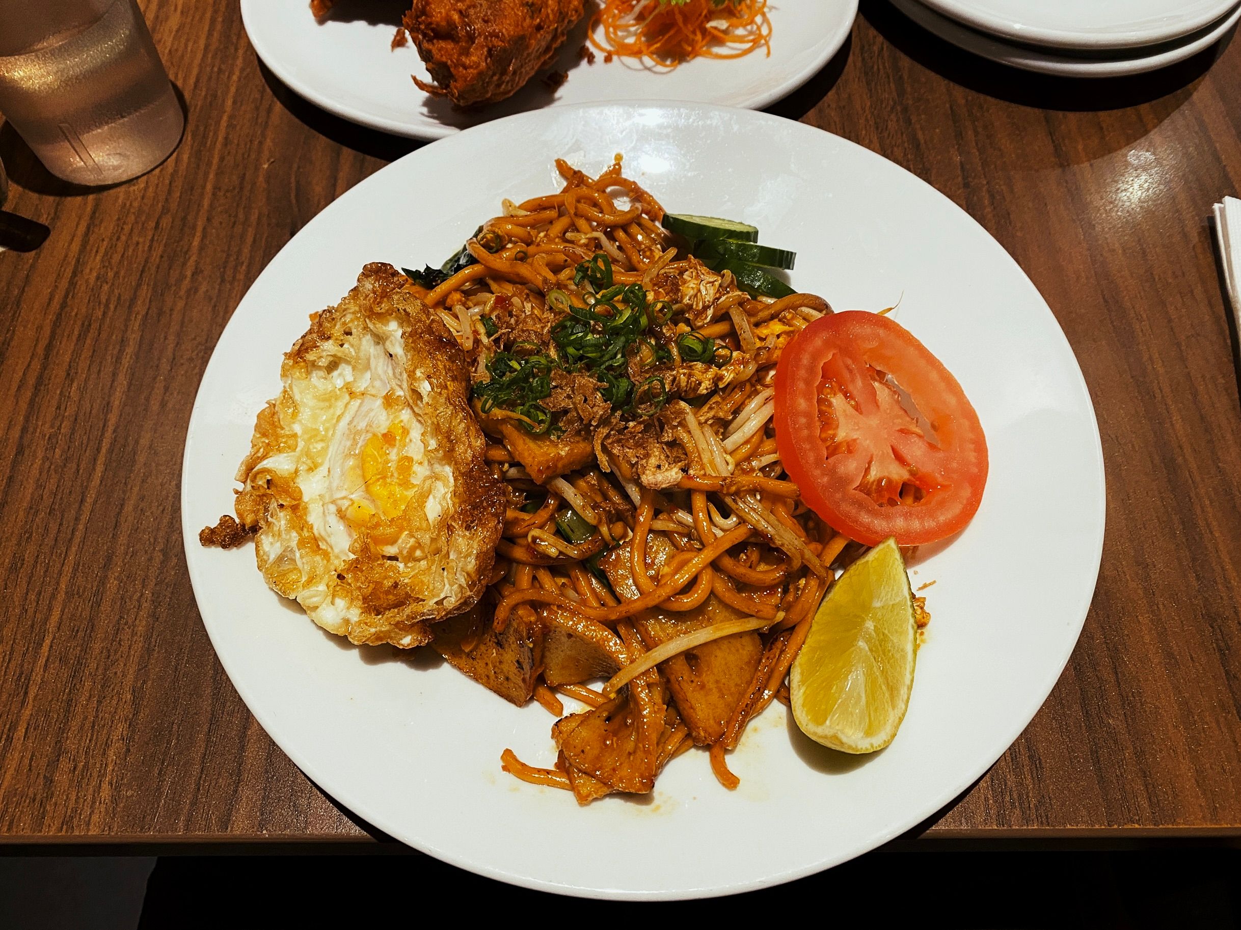 A photo of mee goreng on a plate with a fried egg on top.