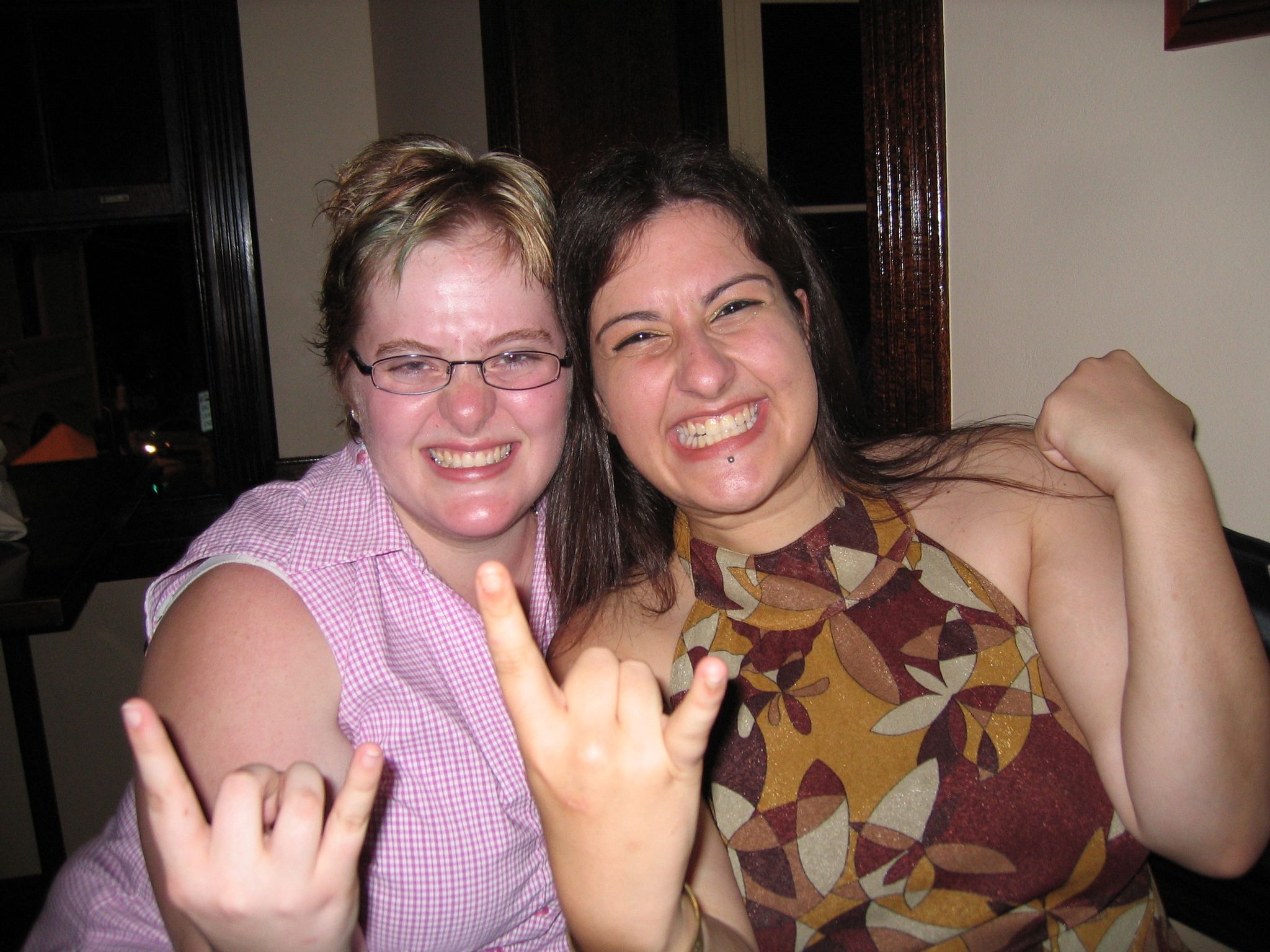 A photo of two women grinning and throwing the horns.