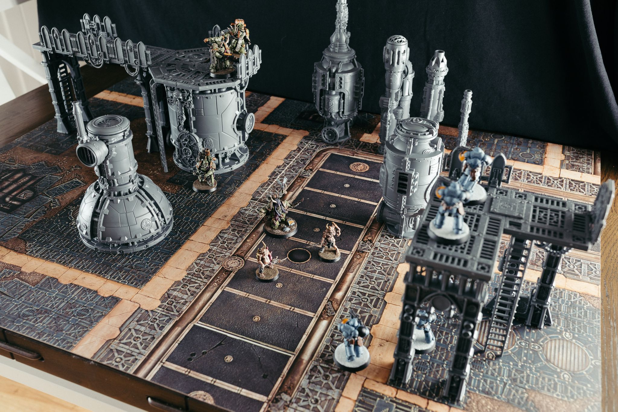 A photo of some Death Guard and Space Wolves miniatures on the new Kill Team starter box terrain. The terrain itself is unpainted grey plastic but is towering over the miniatures and has a very steampunk aesthetic to it.