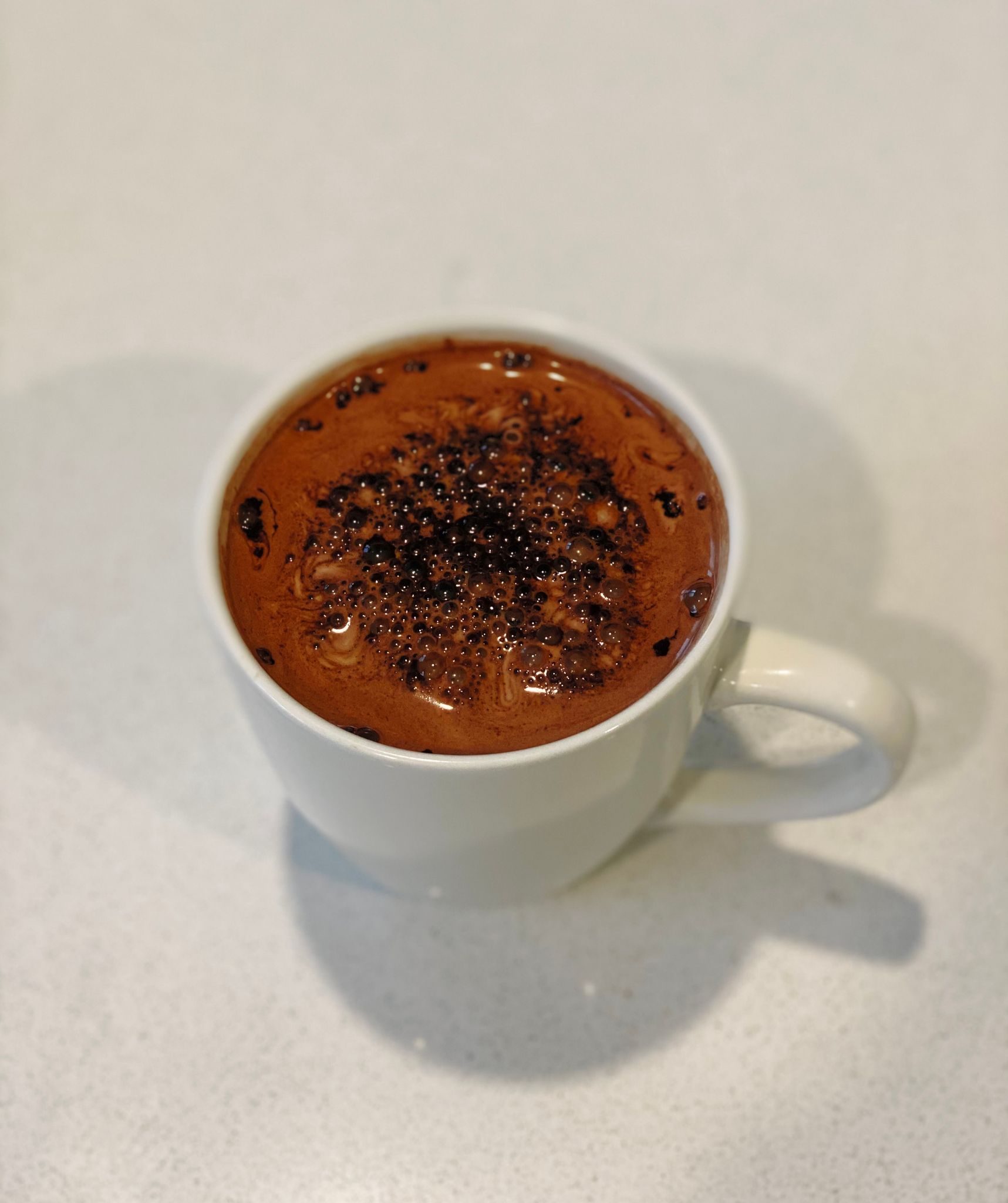 A photo of a mug of hot chocolate sitting on a bench.