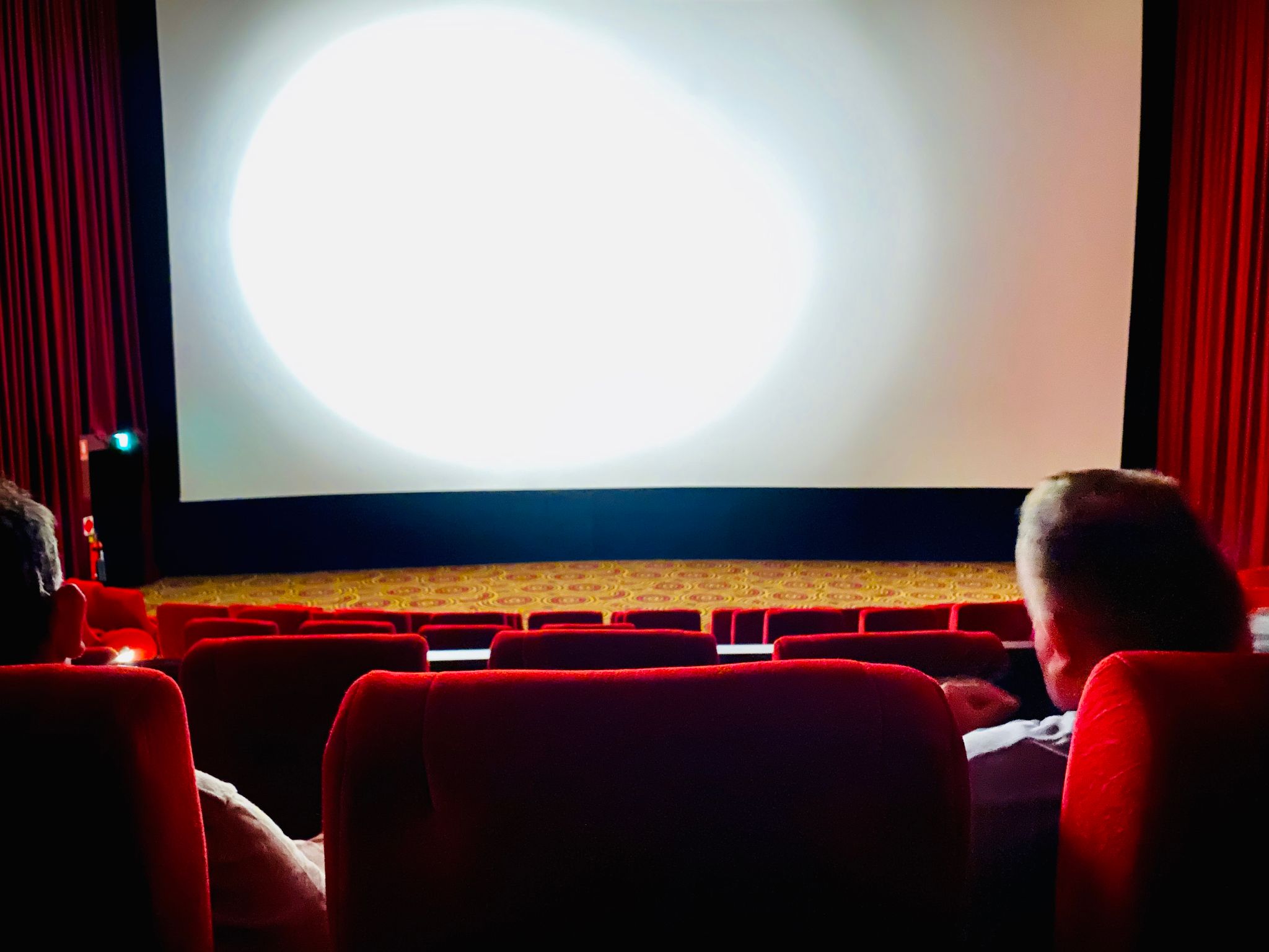 A photo in a cinema looking down towards the currently-empty screen.
