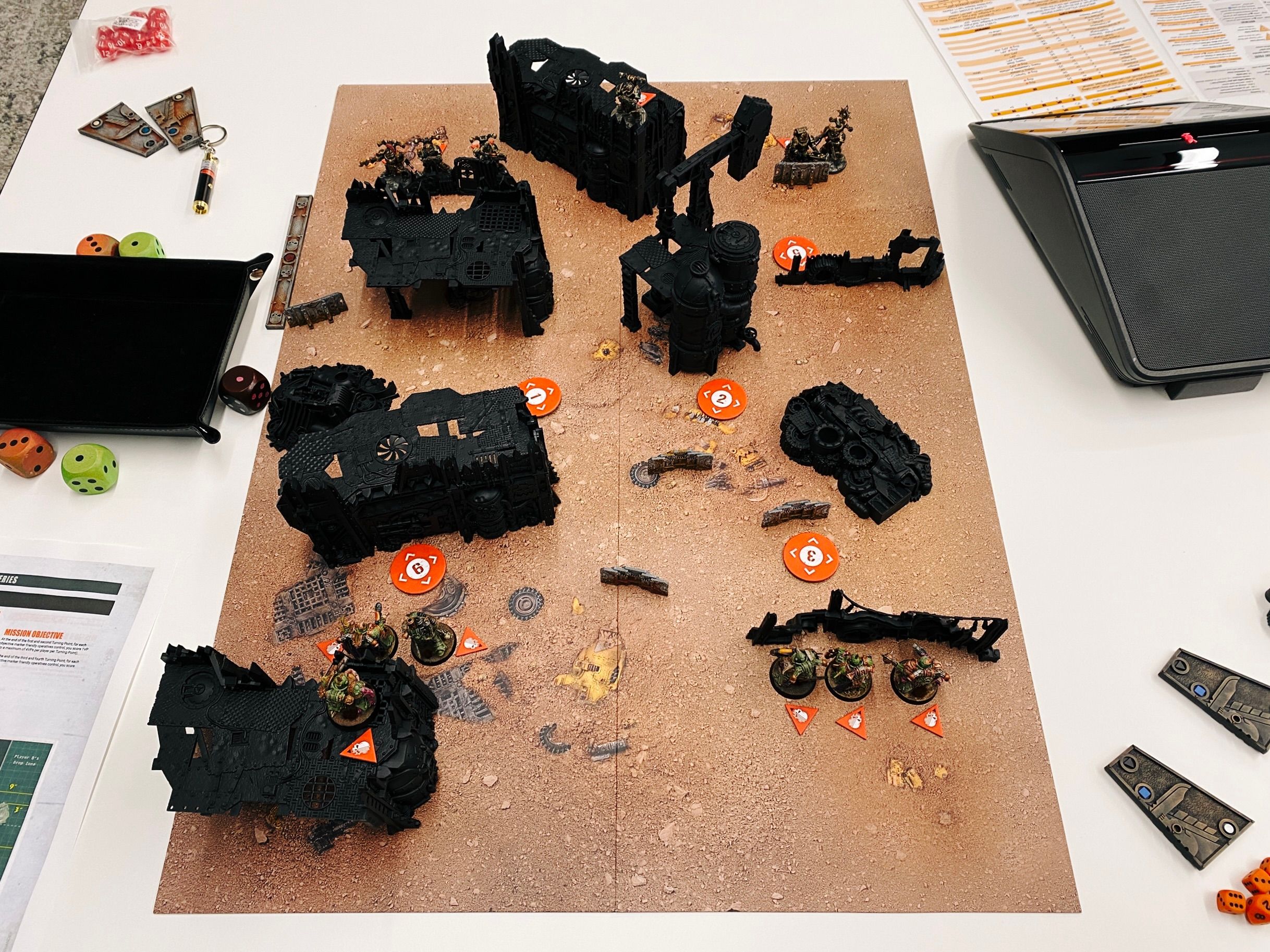A photo of a Warhammer 40,000 game board, with painted miniatures and shamefully unpainted terrain that looks like a junkyard on it.