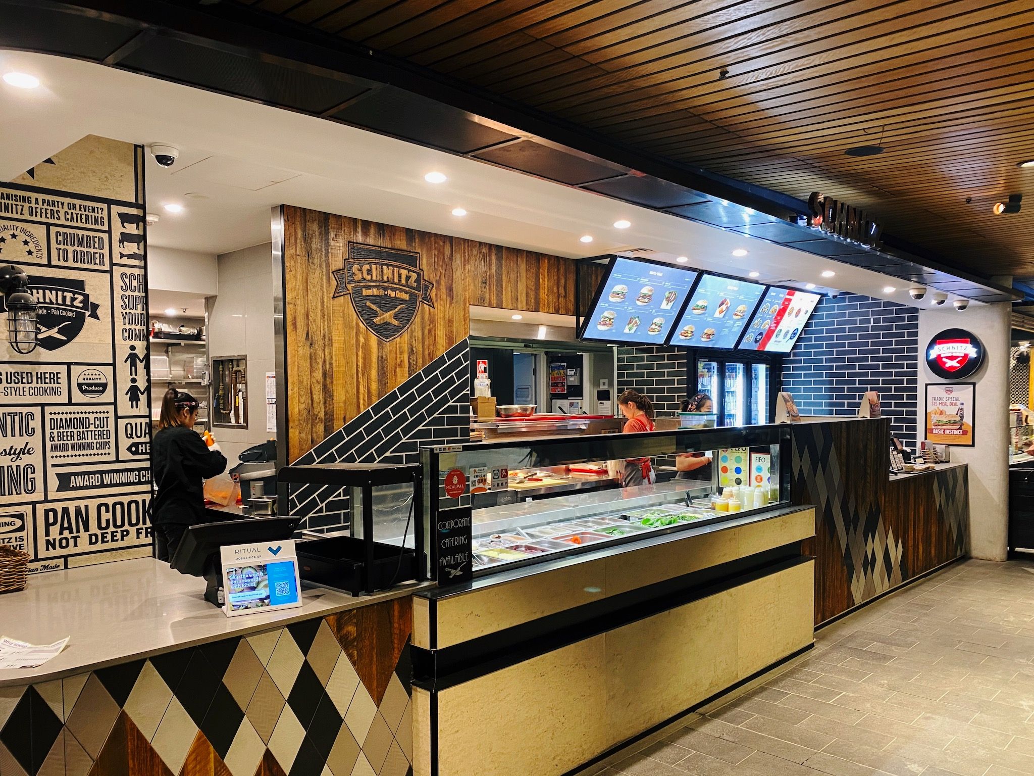 A photo of the fast food outlet Schnitz in the MLC Centre in Sydney's CBD. It's set up similar to Subway, with a salad bar-type setup at the front where they prepare the wrap or roll, and a kitchen in the back where the schnitzel is cooked. There's nobody else waiting there apart from me.