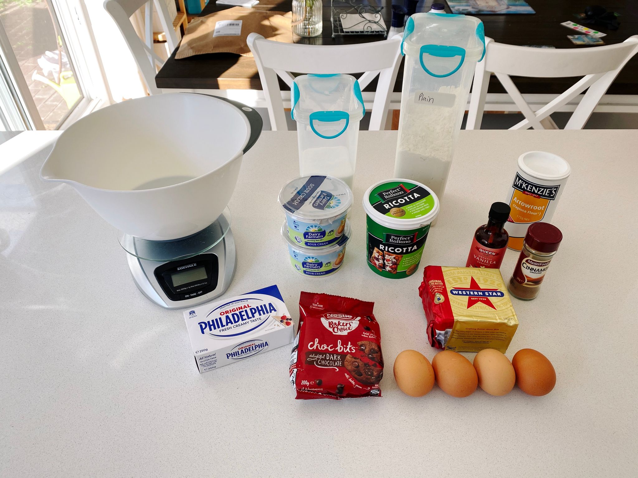 A photo of the ingredients required for cheesecake, all sitting out on a bench.