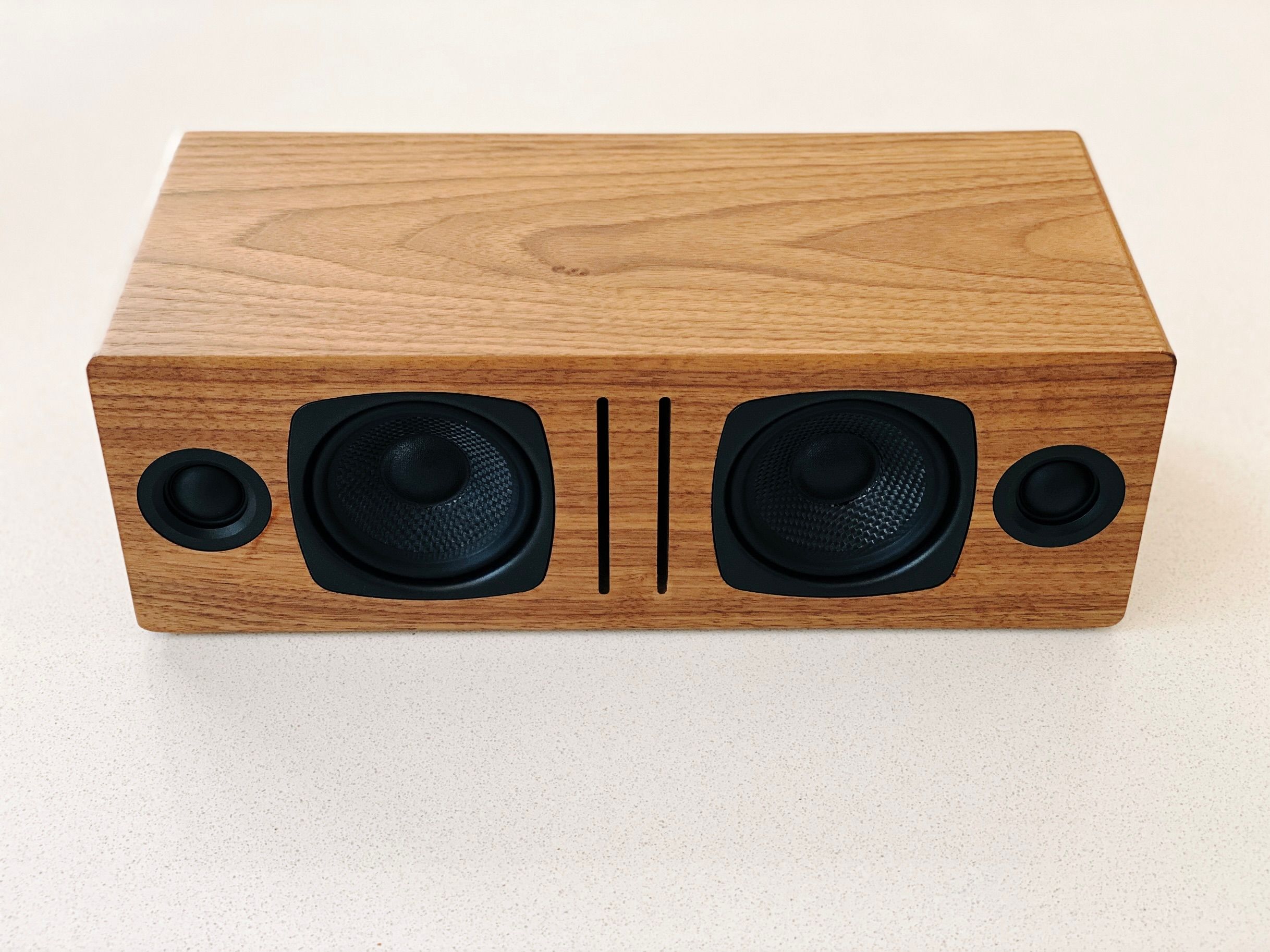 The same speaker but without the grill, showing the individual speakers inside it. There's two woofers towards the middle, and two tweeters on either end.