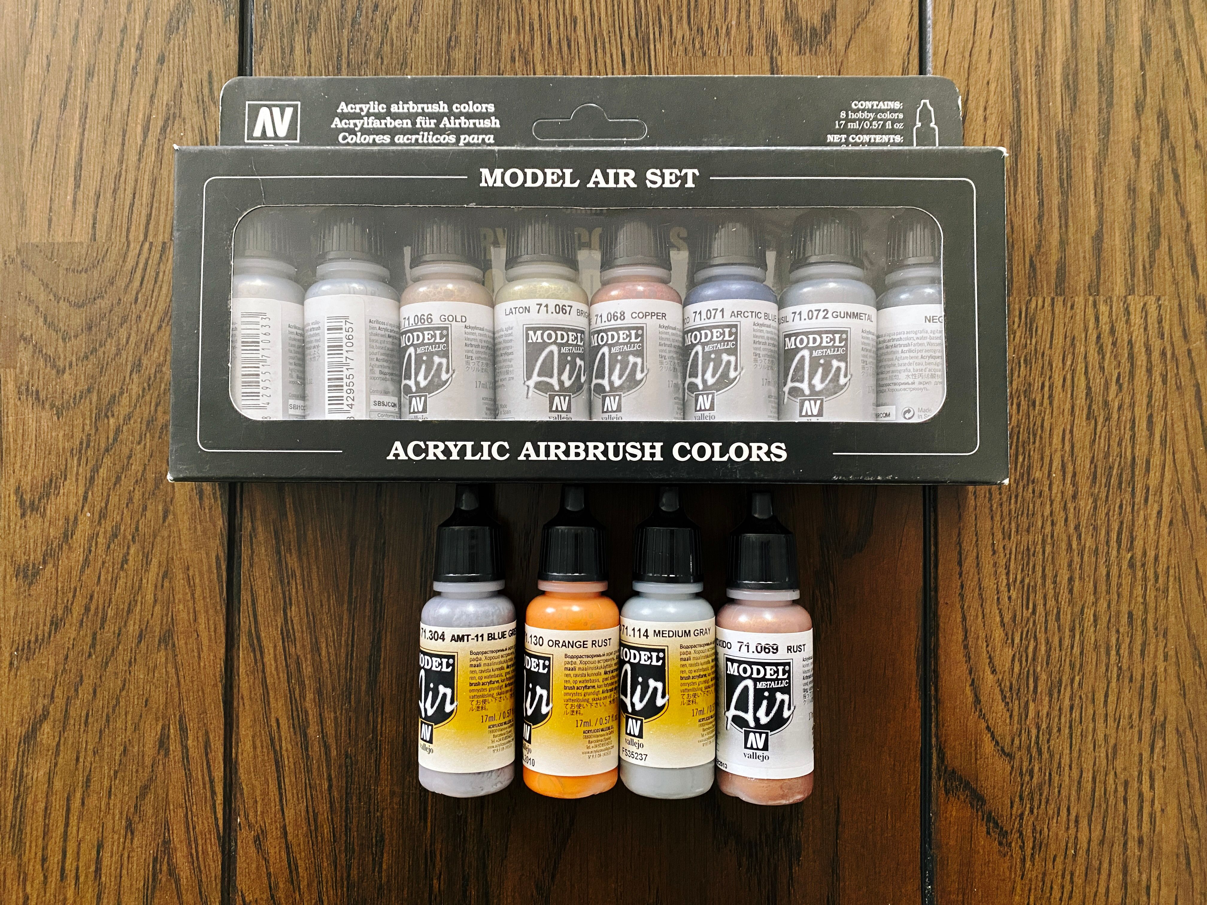 A photo of box of eight Vallejo metallic airbrush paints in various shades, plus a medium grey, blue grey, rust, and orange rust.