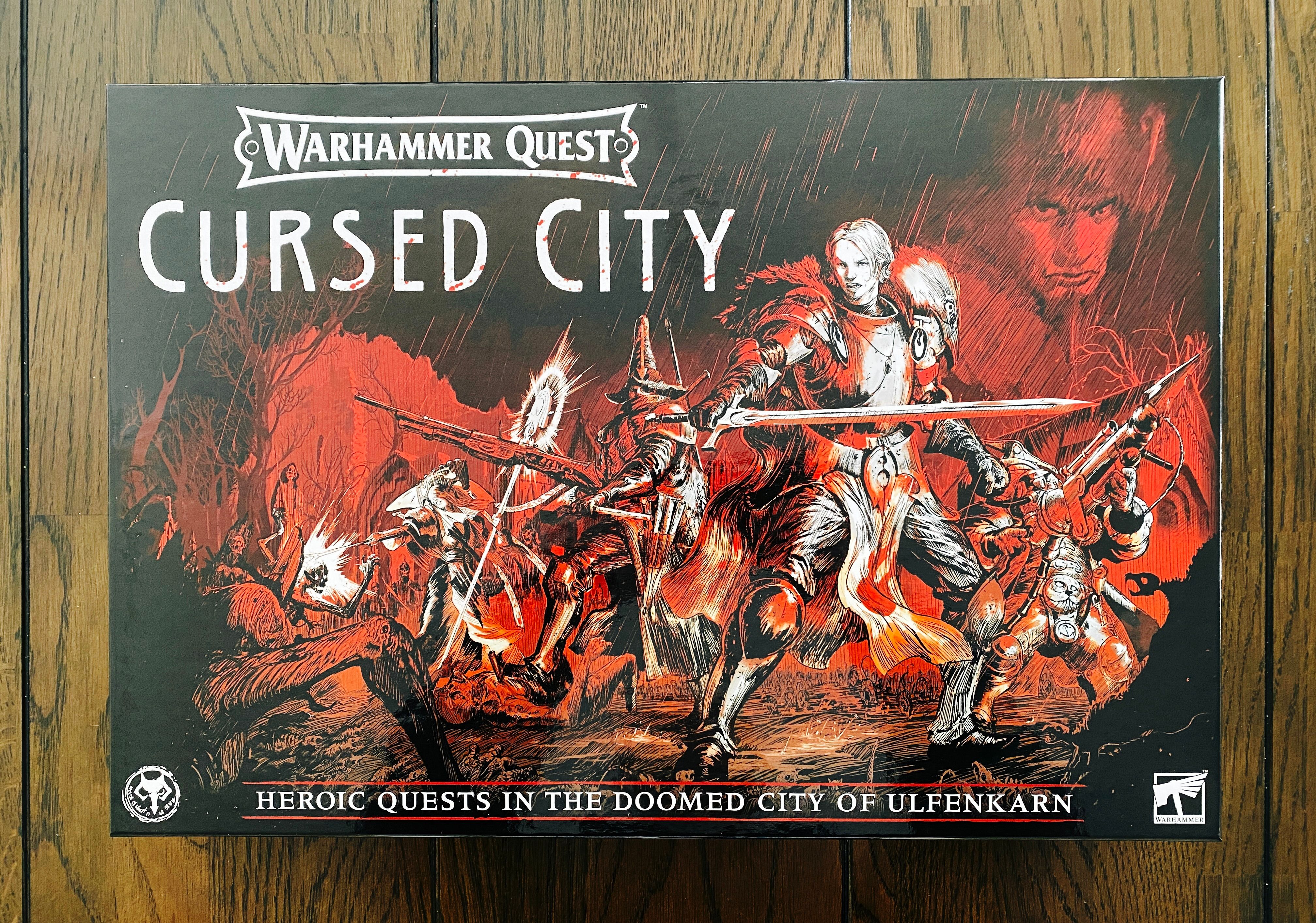 A photo of the box of Warhammer Quest: Cursed City. The artwork on the front is done in a pencil style primarily in red tones, and has several fantasy heroes in the middle battling off the skeletons that are lurking in the shadows to the sides.

The game itself is a co-op dungeon crawler and the box weighs a TON.