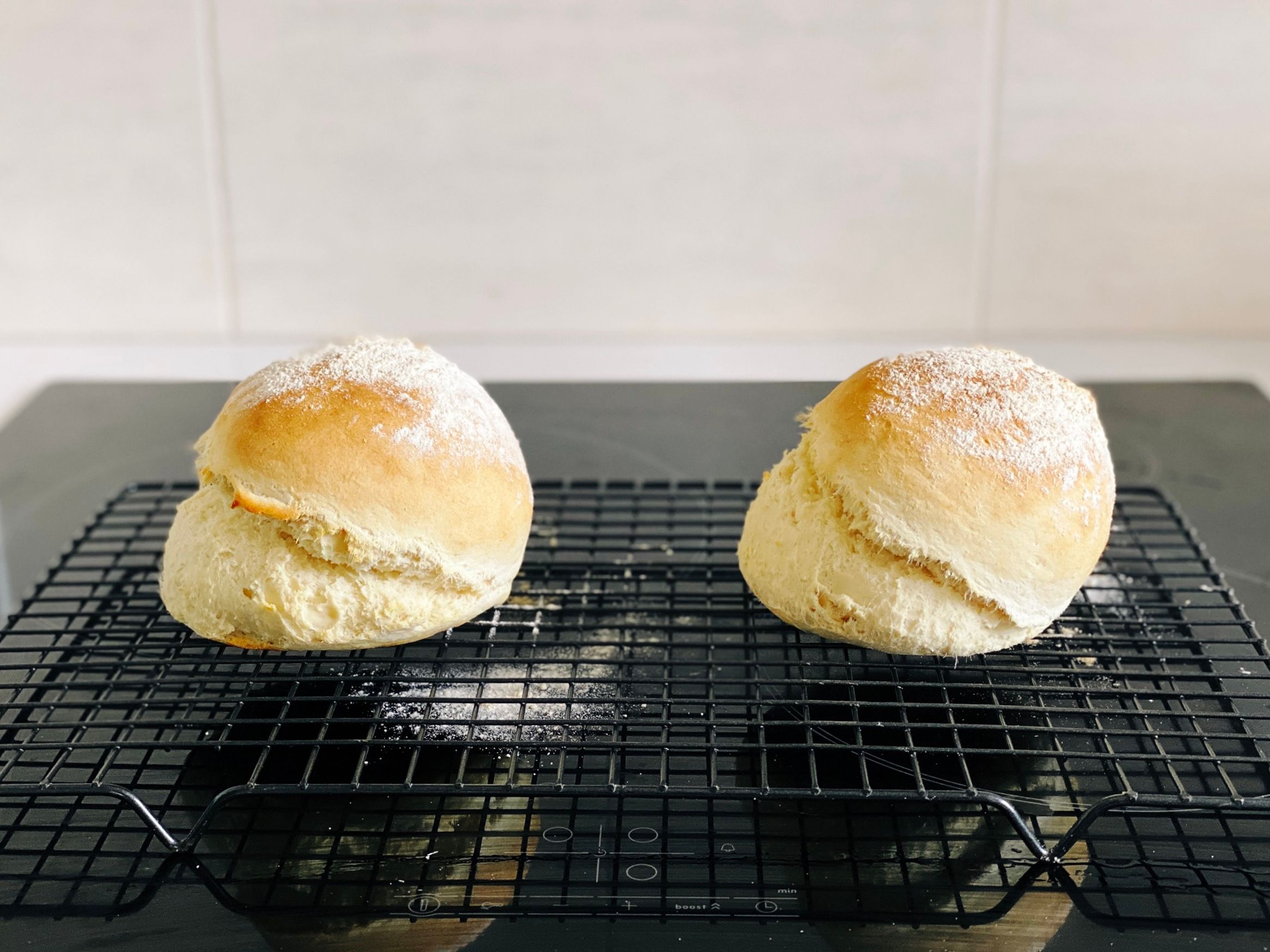 A photo of two pieces of damper (essentially very basic bread), with flour on top. They've split weirdly in the middle along the horizontal axis though, so it looks like the top half is slowly sliding off the bottom.