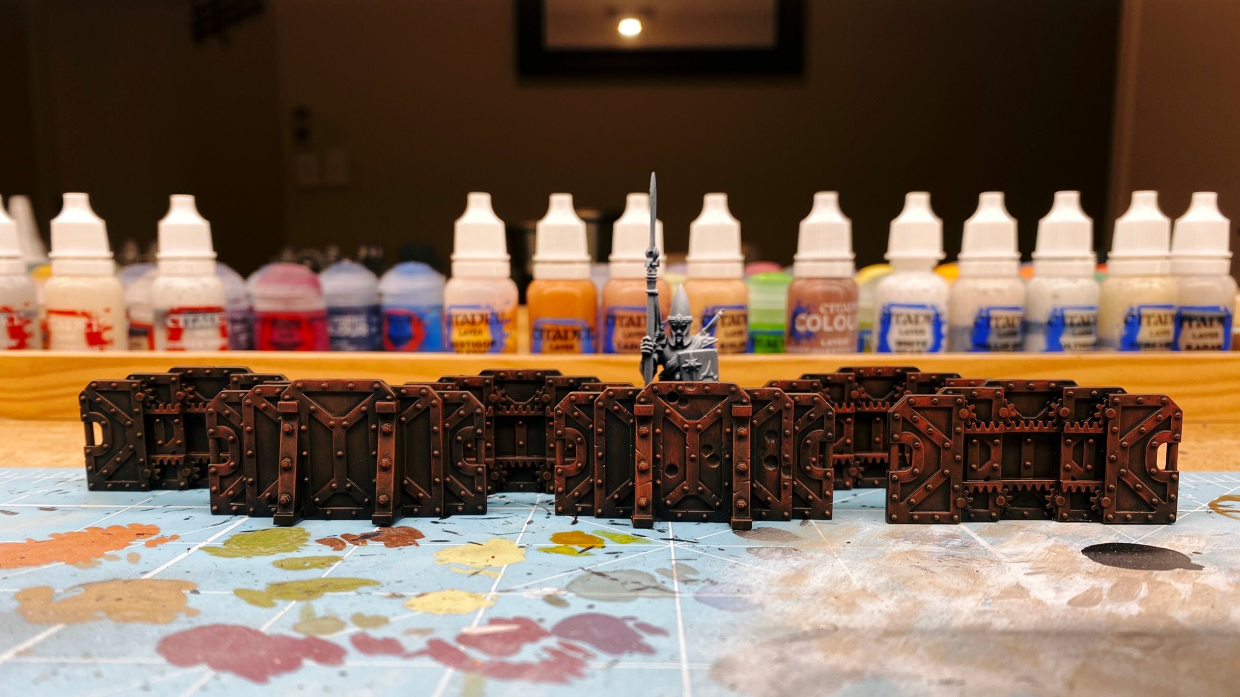A photo of six barricades that come up to about chest height on the miniature that's standing behind them. They're all segmented and gears and teethed tracks on the inside that makes it looks like they can be expanded or collapsed in width. They're all painted in brown and look like they're completely rusty.