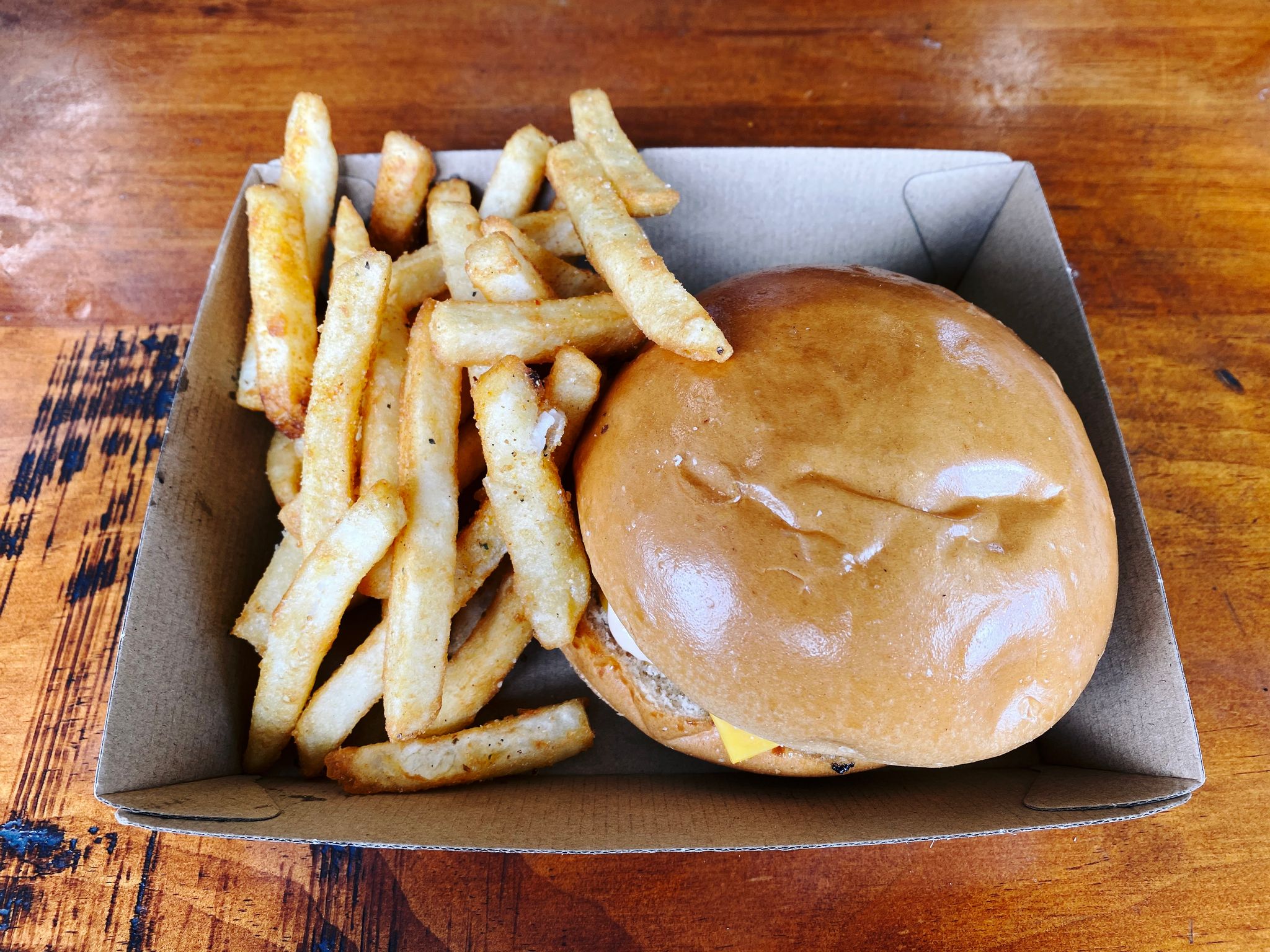 A photo of a burger and chips in a brown cardboard box.