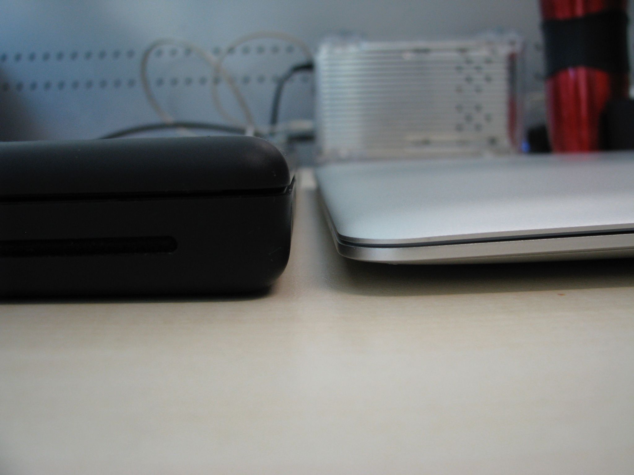 A photo taken from the side of the thin end of a first-generation MacBook Air sitting next to a black polycarbonate MacBook.