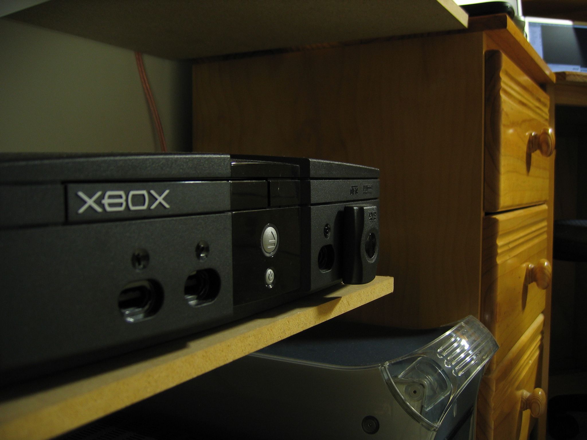 A photo of the front of an original Xbox with the DVD remote receiver attached to one of the controller ports, taken at a sharp angle from the side.