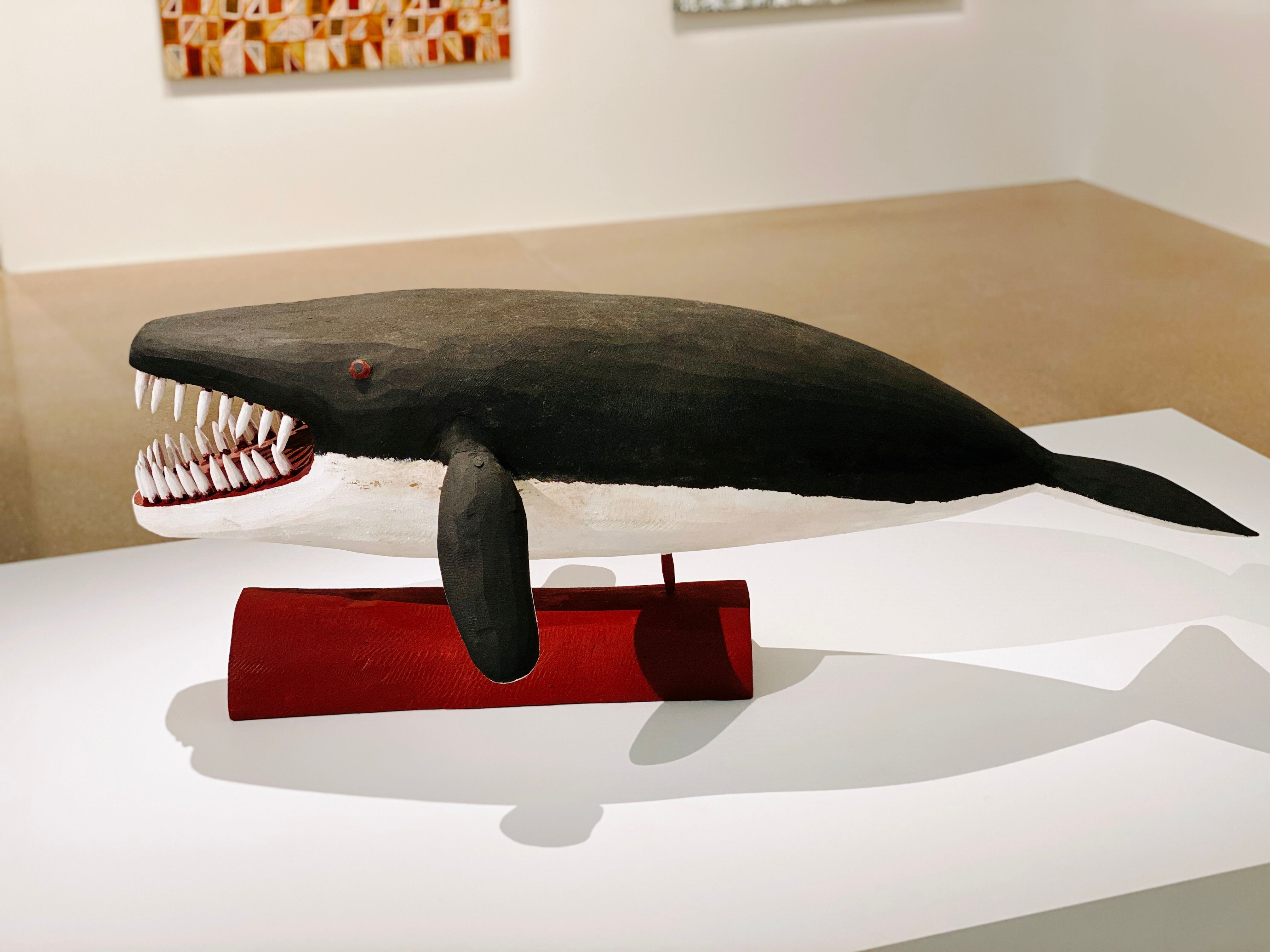 A photo of a stylised sculpture of a black and white whale, it's short and stubby and has big teeth for some reason.