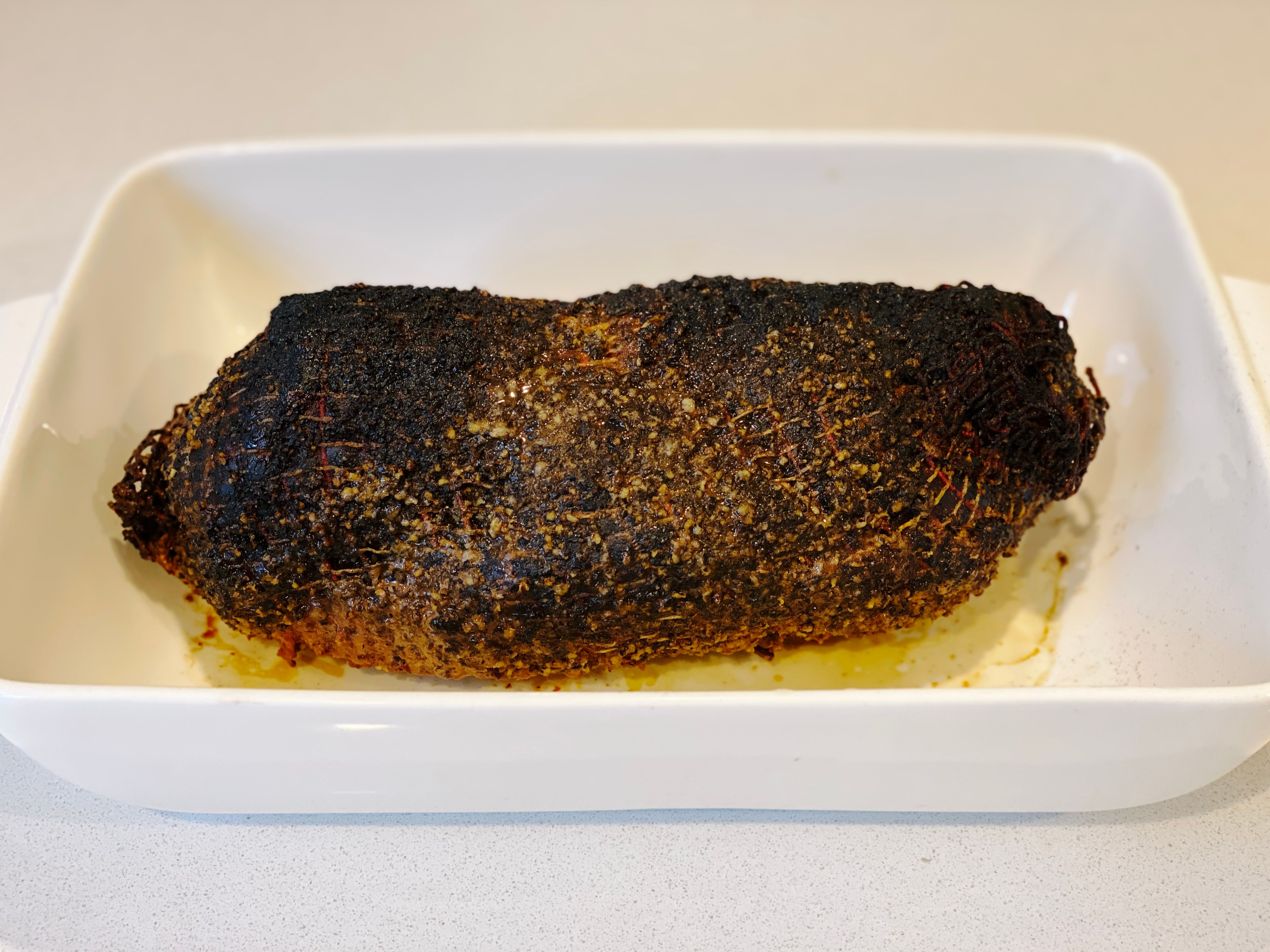 A photo of a pork collar butt that's been smoked, it's blackened and looks amazing.